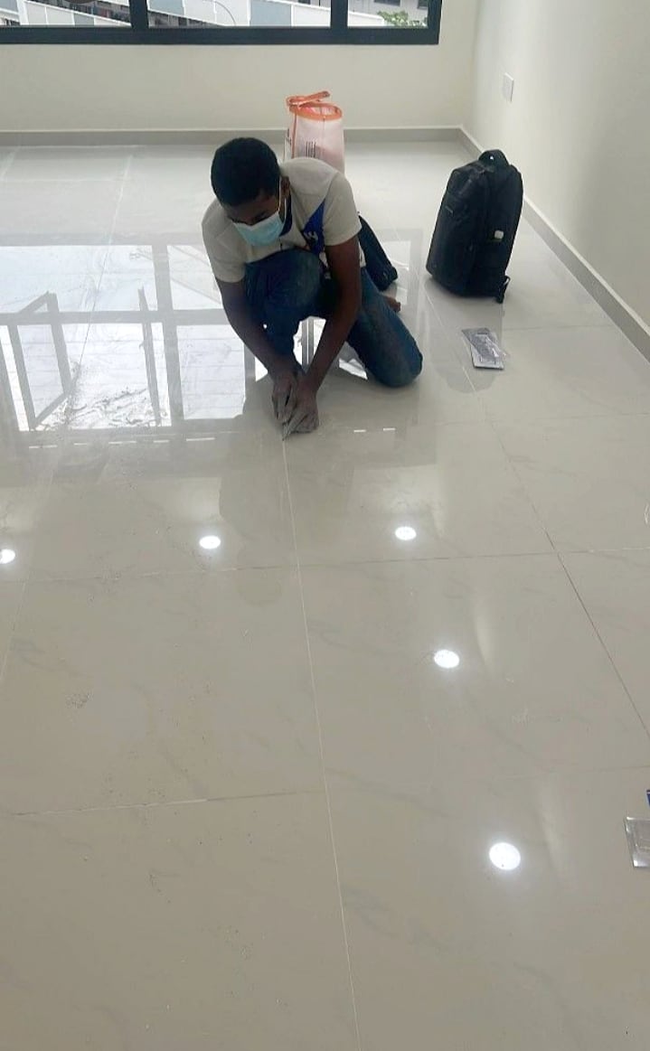 Technician cleaning and preparing floor tile joints for regrouting
