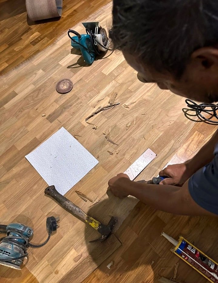 Technician carrying out detailed parquet repair by hand