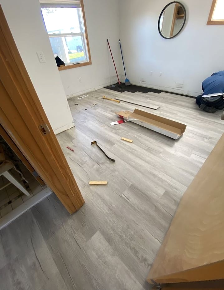 Grey vinyl room installation with planks and tools on site